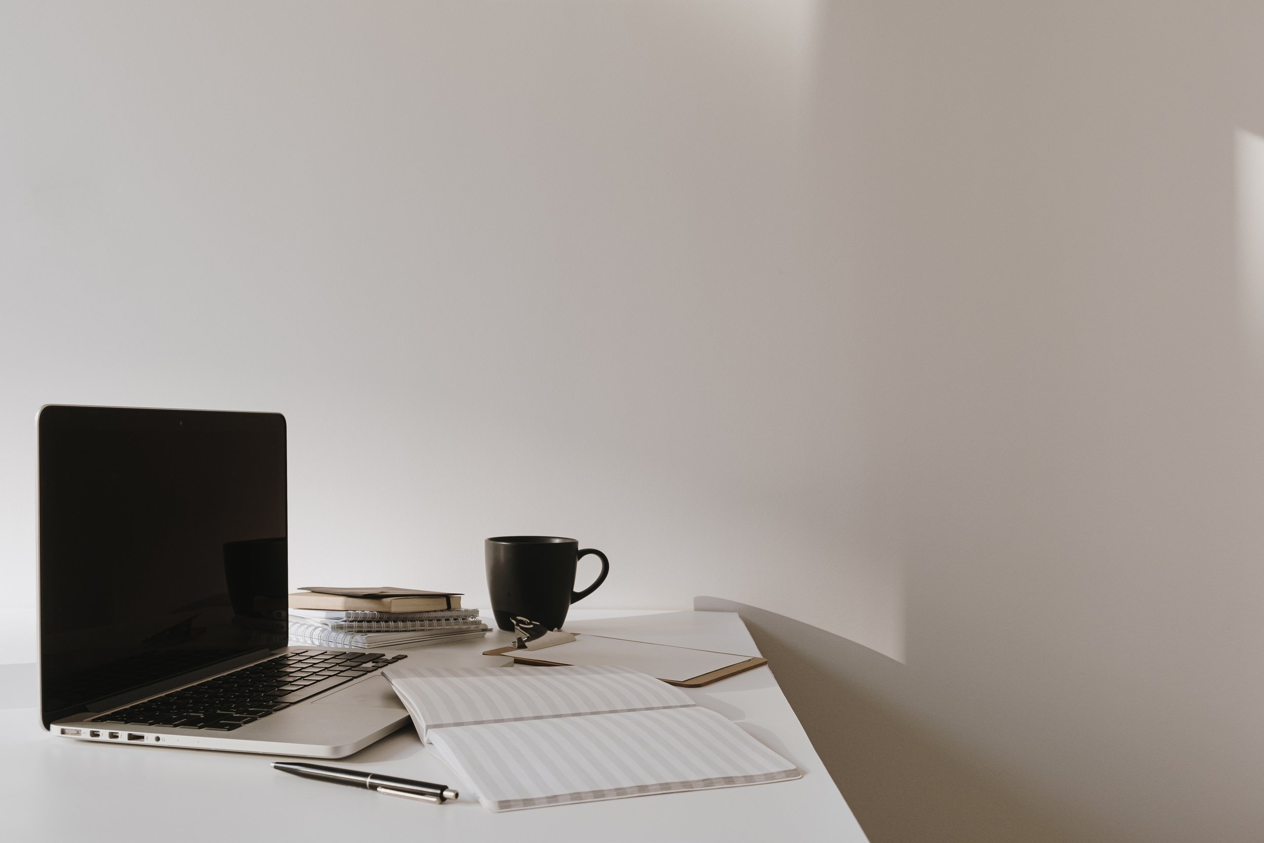 Laptop, Notebook, Cup, and Ball Pen on a Table